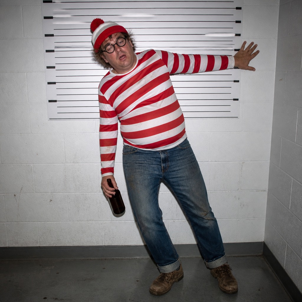Verified original artwork number 911: Drunk Waldo leaning against a booking-room height chart, holding a bottle.